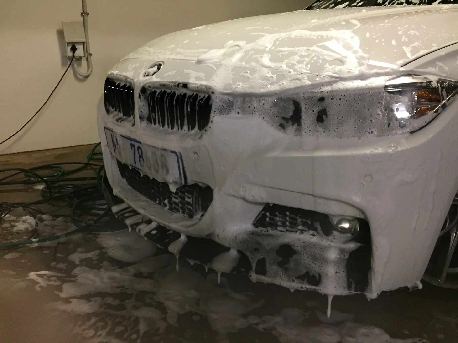White BMW saloon covered in foam during an exterior wash