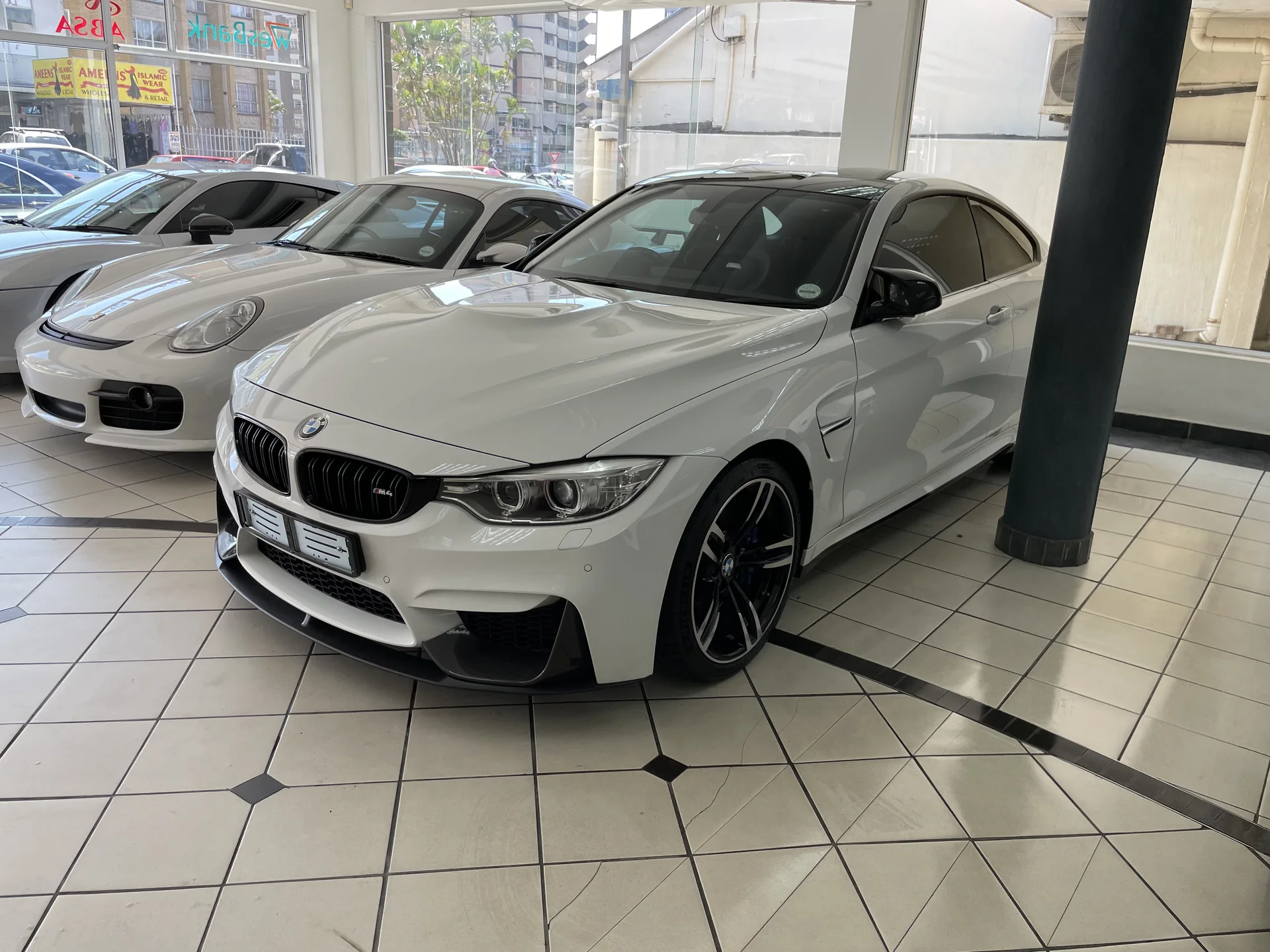 White BMW performance car and white sports car at a dealership